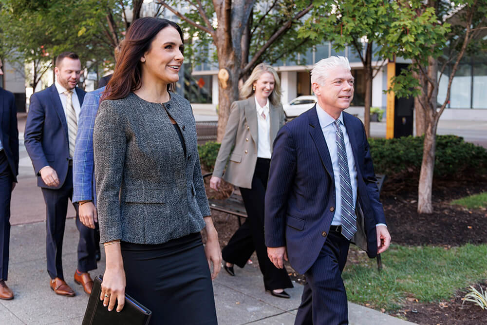 Four attorneys talking and walking together in a city park.